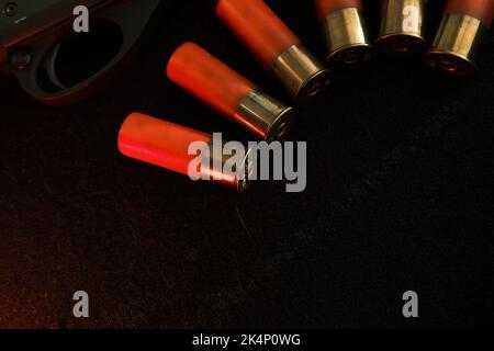 Déclenchement d'une carabine sur fond noir avec un éclair rouge avec des carabines Shotgun sur une surface noire. Munitions pour armes à smoothbore de calibre 12. Chasse Banque D'Images