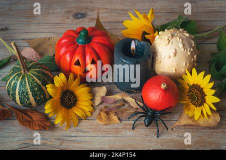 Décoration festive Halloween avec Jack-O-Lantern, citrouilles, bougie, tournesol et araignée sur une table en bois. Concept des vacances d'automne. Vue de dessus. Banque D'Images