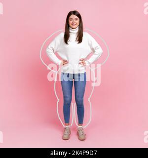 Soins du corps, amincissement et entraînement. Portrait en longueur de la femme se noie autour, appréciant le résultat de la perte de poids, debout avec les mains sur les hanches. Studio d'intérieur isolé sur fond rose. Banque D'Images