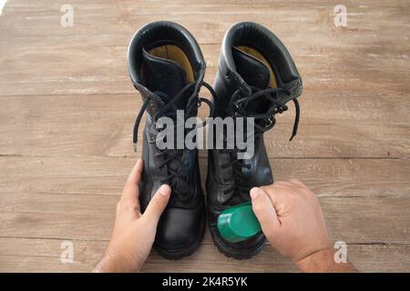 Image des mains d'un homme qui polit une paire de bottes militaires avec une brosse à chaussures. Banque D'Images