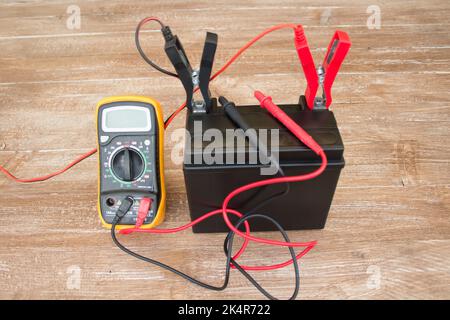 Illustration d'une batterie en charge. Charger une batterie au plomb pour les voitures et les motos à l'aide d'un multimètre pour mesurer sa charge Banque D'Images