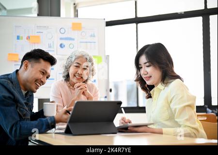 Bonne et professionnelle d'âge asiatique patron ou directeur exécutif, satisfait de ses résultats de campagne de marketing dans la réunion avec son te de marketing Banque D'Images