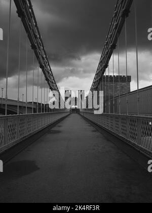 Un cliché vertical en niveaux de gris du pont suspendu du château de Conwy sous ciel couvert, Royaume-Uni Banque D'Images