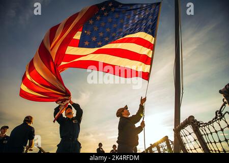 Riga, Lettonie. 18th septembre 2022. Les marins de la Marine américaine affectés au destroyer de missiles guidés de classe Arleigh Burke USS Paul Ignatius (DDG 117) abaissent l'enseigne pendant la mer et les détails d'ancrage alors que le navire quitte Riga, Lettonie après une visite prévue du port, le 18 septembre 2022. Paul Ignatius fait partie du Kearsarge Amphiobie Ready Group et a embarqué 22nd Marine Expeditionary Unit, sous le commandement et le contrôle de Task Force 61/2, dans un déploiement prévu dans la zone des opérations de la Marine américaine Europe, employée par la U.S. Sixth Fleet pour défendre les intérêts américains, alliés et partenaires. (Image de crédit : © États-Unis Banque D'Images