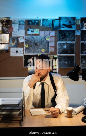 Enquêteur sérieux ou détective travaillant au bureau, analysant les informations d'une enquête sur une affaire criminelle Banque D'Images