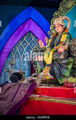 Une femme touchant les pieds d'une idole de Maa Durga à un mandal à Mumbai pour le festival indien de Navratri Banque D'Images