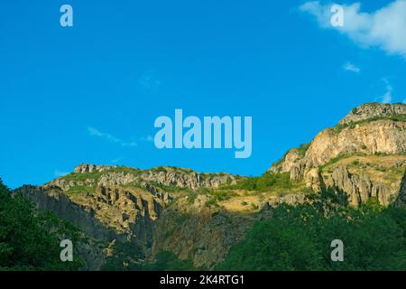 Montagnes rocheuses et boisées près du monastère de Geghard, par une journée ensoleillée et nuageux, au coucher du soleil, pendant l'heure d'or Banque D'Images