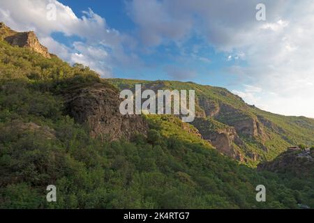 Montagnes rocheuses et boisées près du monastère de Geghard, par une journée ensoleillée et nuageux, au coucher du soleil, pendant l'heure d'or Banque D'Images