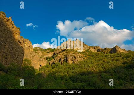 Montagnes rocheuses et boisées près du monastère de Geghard, par une journée ensoleillée et nuageux, au coucher du soleil, pendant l'heure d'or Banque D'Images