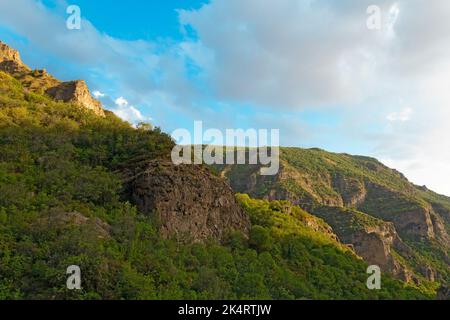 Montagnes rocheuses et boisées près du monastère de Geghard, par une journée ensoleillée et nuageux, au coucher du soleil, pendant l'heure d'or Banque D'Images