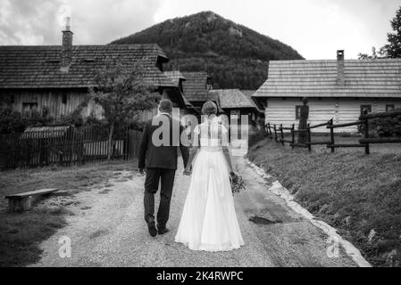 une mariée et un marié tenant les mains et marchant ensemble à travers la campagne. photographie en noir et blanc Banque D'Images