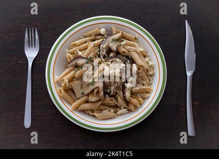 Pâtes aux champignons sur fond de bois. Champignons porcini avec fromage, romarin et ail sur l'assiette. Banque D'Images