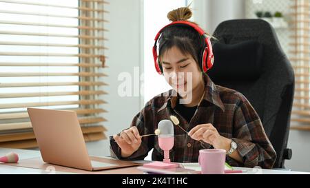 Femme asiatique en casque d'écoute pour faire des sons ASMR dans un studio à domicile. Déclencheurs de relaxation et sons pour soulager le stress concept Banque D'Images