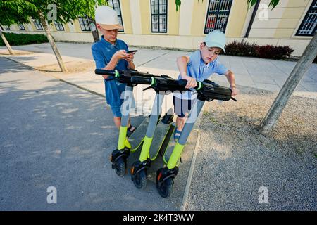 Deux frères paient pour les scooters électriques de voyage à Vienne, en Autriche. Banque D'Images