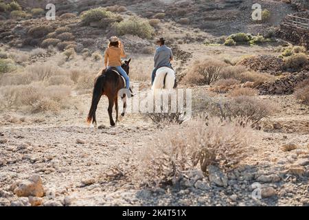 Jeunes à cheval faisant l'excursion au coucher du soleil - Focus sur le dos de la femme. Banque D'Images