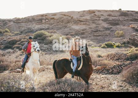 Jeune couple équitation chevaux faisant l'excursion au coucher du soleil - Focus sur le visage de la femme. Banque D'Images