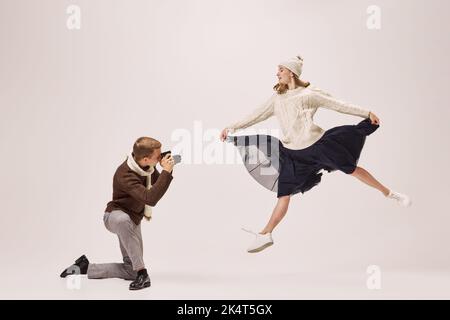 Jeune photographe élégant prenant la photo de jeune ballerine gracieux isolé sur fond gris. Rétro, vintage, danse, vacances, concept de fête Banque D'Images