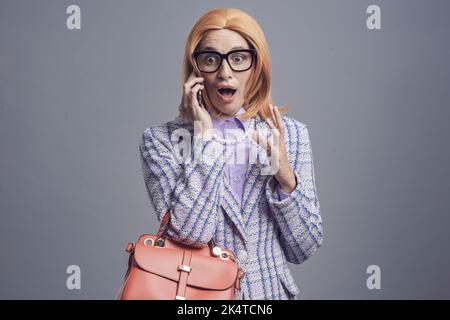 Drôle à la mode femme parlant et commératant au téléphone, elle reçoit des nouvelles choquantes Banque D'Images