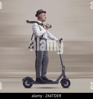 Homme de style vintage portant une valise et portant un scooter électrique, il est un voyageur et un photographe Banque D'Images