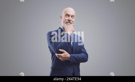 Homme d'affaires d'entreprise pensant main sur main, opportunités et concept de solutions d'affaires, isolé sur fond gris Banque D'Images