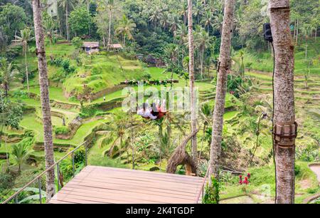 Un couple asiatique assis au-dessus de la terrasse de riz de Tegalalang est l'un des objets touristiques célèbres à Bali situé dans le village de Tegalalang au nord d'Ubu Banque D'Images