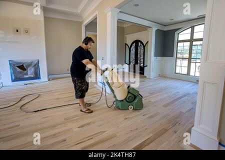 Le procédé de meulage d'un parquet en bois en utilisant une ponceuse de plancher de la maison nouvellement construite Banque D'Images