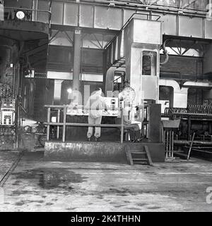 Années 1950, historique, à l'intérieur d'une aciérie, un opérateur à une unité de contrôle, et un jeune homme assis prenant des notes des lectures de données à l'Abbey Works, de la Steel Company of Wales (Scow), Port Talbot, pays de Galles, Royaume-Uni. Banque D'Images