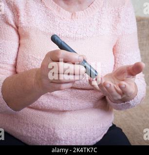 Femme âgée vérifiant le taux de sucre dans le sang à l'aide d'un glucomètre. Gros plan main de la personne âgée avec le diabète. Traitement du diabète chez les personnes âgées. Banque D'Images