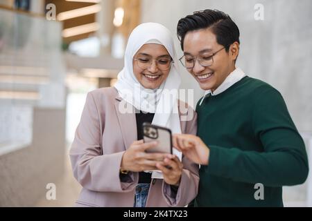 Un jeune couple souriant utilisant un smartphone ensemble Banque D'Images