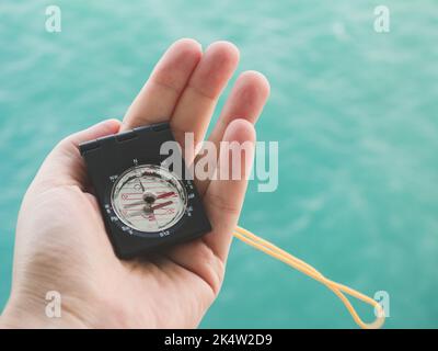 Main de femme et boussole sur le fond des vagues de mer. Vue de dessus, gros plan. Concept de vacances et de voyages Banque D'Images