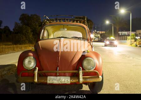 Une vieille Volkswagen ou VW Beetle garée sur la roadhouse la nuit. Il n'y a personne avec la vieille voiture classique et elle est éclairée par les feux de rue à proximité Banque D'Images