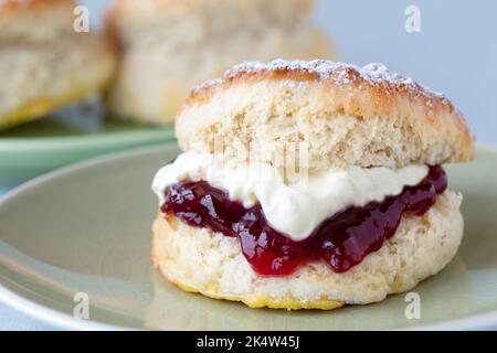 Un scone frais et traditionnel anglais fait maison. Le gâteau est fendu et rempli de confiture et recouvert de crème épaisse épaisse. Un délicieux thé à la crème de Cornouailles. Banque D'Images