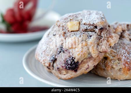 Des scones frais faits maison de pomme et de mûre, servis plaquées avec une tasse de thé dans une tasse de porcelaine. Cuisiné à partir d'un livre de recettes de confiance nationale Banque D'Images