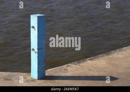 Poteau en béton avec crochets à chaînes sur la jetée, poteau bleu Jetty, piliers en béton bleu avec lumière du soleil. Banque D'Images