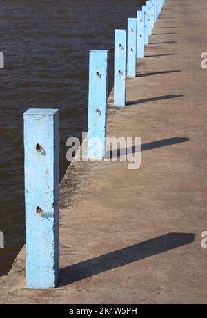 Poteau en béton avec crochets à chaînes sur la jetée, poteau bleu Jetty, piliers en béton bleu avec lumière du soleil. Banque D'Images