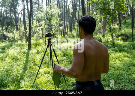 Athlète d'âge moyen mature homme debout dans des vêtements de sport sur le tapis de fitness, regardant la vidéo tutoriel d'entraînement en ligne, vlogging Banque D'Images