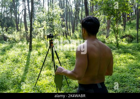 Athlète d'âge moyen mature homme debout dans des vêtements de sport sur le tapis de fitness, regardant la vidéo tutoriel d'entraînement en ligne, vlogging Banque D'Images