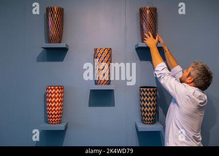 Londres, Royaume-Uni. 4 octobre 2022. Un membre du personnel apporte des ajustements aux « vases romains et byzantins », 2020-2022, par Bottega Vignoli sur le stand de MADEINBRITALY » à la Foire de décoration de Evolution London, Battersea Park. 140 exposants présentent des antiquités, du design et de l'art spécifiquement pour l'acheteur de design d'intérieur dans un salon qui s'étend jusqu'au 9 octobre 2022. Credit: Stephen Chung / Alamy Live News Banque D'Images