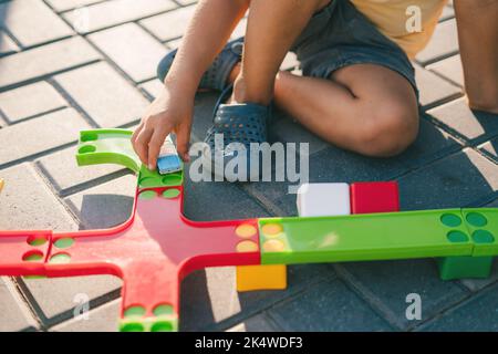 Gros plan d'un garçon jouant dehors avec des jouets en plastique. Transport ferroviaire. Style de vie extérieur. Éducation précoce. Banque D'Images