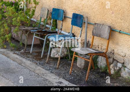 quatre chaises anciennes laissées dehors dans les éléments pour rouille, 4 chaises à l'extérieur d'un bâtiment rural en grèce, chaises rouillant dans la pluie laissée à l'extérieur. Banque D'Images