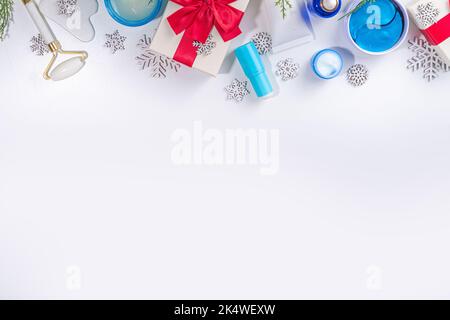 Cosmétiques de soin de la peau et des mains d'hiver dans des contenants sans marque, des bouteilles, des tubes avec flocons de neige artificiels, des branches d'arbre de Noël et des boîtes-cadeaux. CH Banque D'Images
