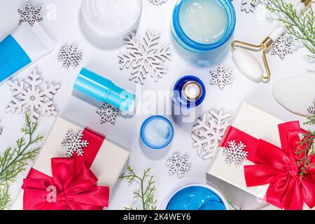 Cosmétiques de soin de la peau et des mains d'hiver dans des contenants sans marque, des bouteilles, des tubes avec flocons de neige artificiels, des branches d'arbre de Noël et des boîtes-cadeaux. CH Banque D'Images