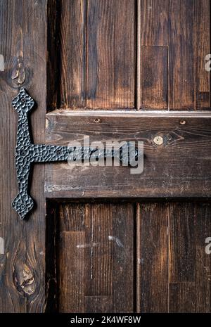 Une vieille porte en bois brun, brun, naturel, avec des grains et une charnière en métal noir, pour le fond et la texture. Photo de haute qualité Banque D'Images