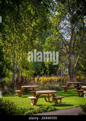 Tables de pique-nique rondes en bois dans un jardin britannique, en été. Banque D'Images