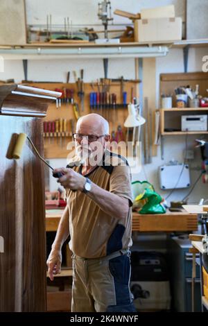 Carpenter antique dans son atelier Oiling A Walnut Baroque Cabinet. Russikon, Suisse Banque D'Images