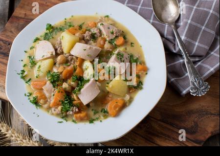 Ragoût salé avec légumes, pommes de terre, pois chiches, saucisse et viande hachée sur une assiette Banque D'Images