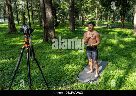 Des yogi masculins actifs et beaux se promène dans un parc en forêt avant ou après un entraînement. Jeune homme sportif hispanique, cours de yoga avec tapis de fitness Banque D'Images