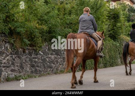 Femme à cheval en premier plan sur le sentier de la campagne Banque D'Images