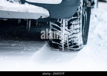 Gros plan des pneus d'hiver d'une voiture sur la route recouverte de neige et de glace, conduite par temps extrêmement froid Banque D'Images