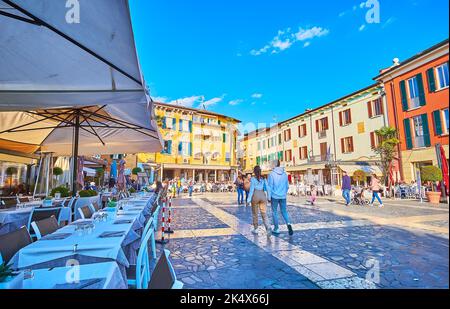 SIRMIONE, ITALIE - 10 AVRIL 2022 : la grande place piétonne Piazza Giogue Carducci est bordée de bâtiments colorés et de terrasses de cafés et restaurants locaux Banque D'Images